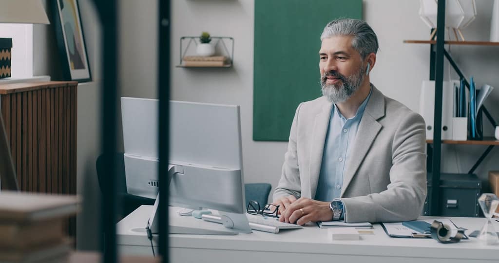 A professional in their 50's sitting at a desk with a laptop